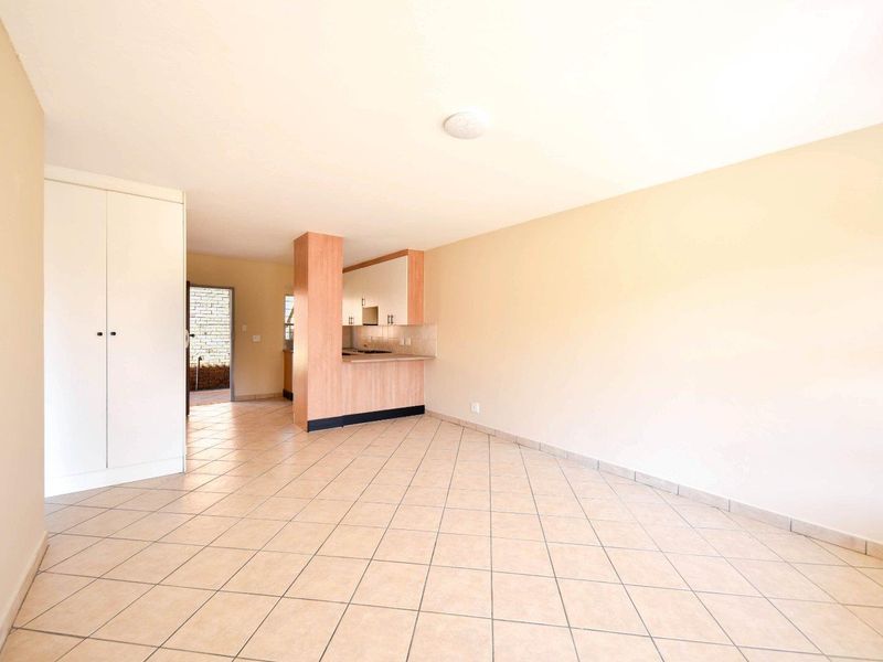 Spacious open-plan living area featuring tiled flooring, built-in storage, and a functional kitchen layout with integrated cabinetry and counter space.