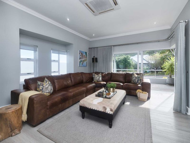 Spacious living room featuring neutral walls, crown molding, recessed lighting, ceiling-mounted air conditioning, and large sliding glass doors leading to an outdoor area.