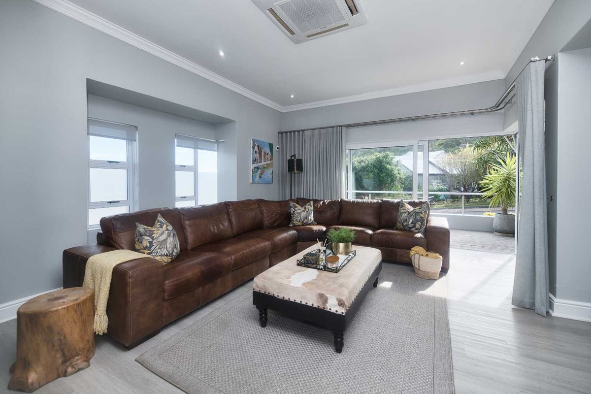 Spacious living room featuring neutral walls, crown molding, recessed lighting, ceiling-mounted air conditioning, and large sliding glass doors leading to an outdoor area.