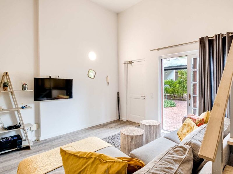 Bright living room featuring high ceilings, laminate flooring, and direct access to an outdoor patio area through a sliding glass door.