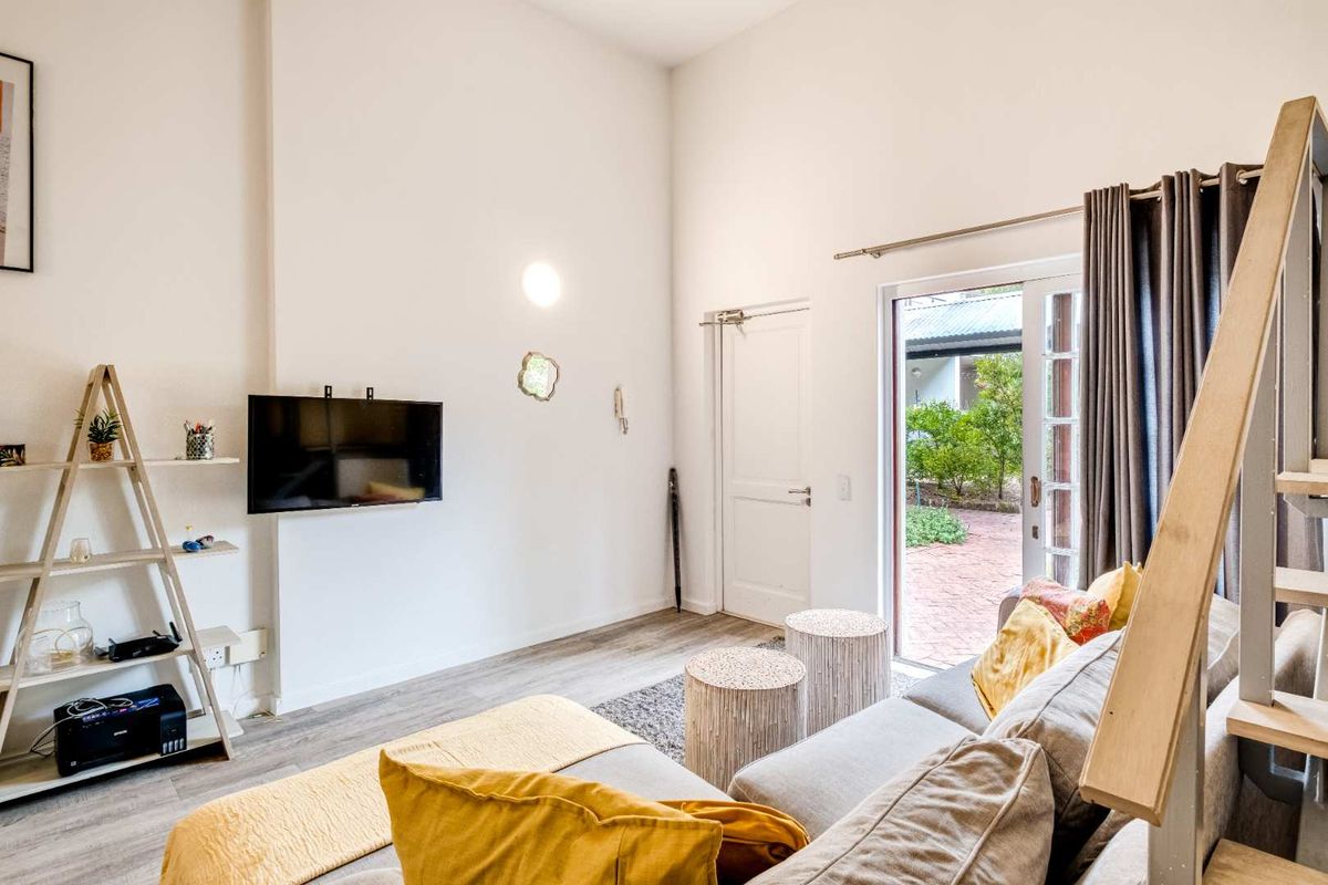 Bright living room featuring high ceilings, laminate flooring, and direct access to an outdoor patio area through a sliding glass door.