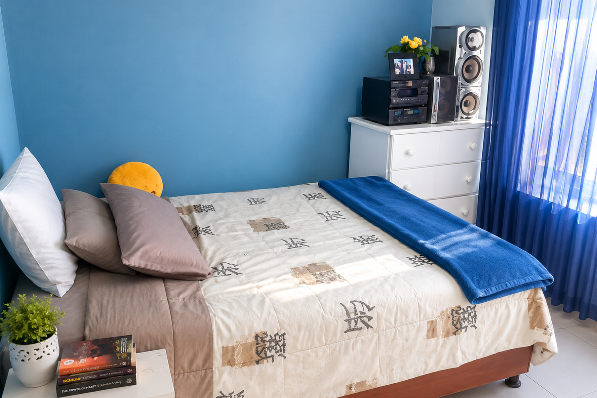 A bedroom featuring blue painted walls, tiled flooring, and blue sheer curtains, providing a simple and functional living space.