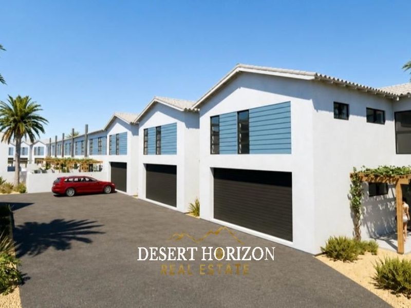 A modern townhouse complex featuring a paved driveway, multiple garage access points, and timber pergola detailing on the exterior facade.