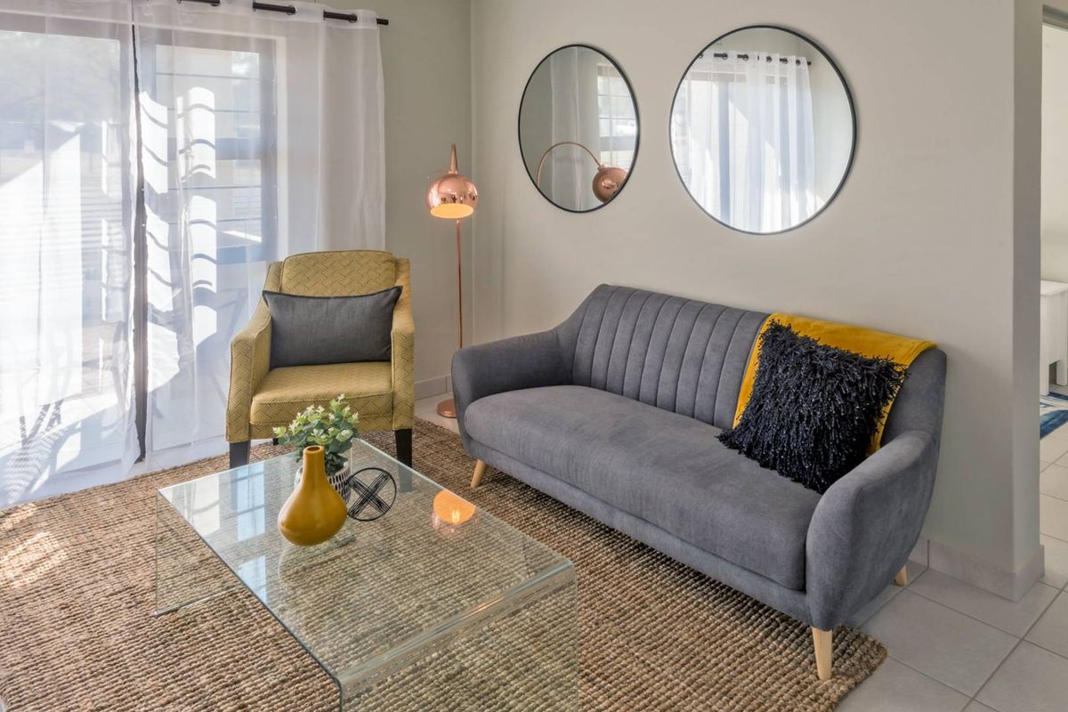 A bright and well-maintained living room featuring tiled flooring and a large sliding glass door providing natural light.