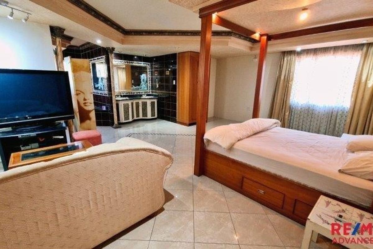 Spacious bedroom featuring tiled flooring, a built-in vanity area with dark tiling, and a recessed ceiling with integrated lighting.