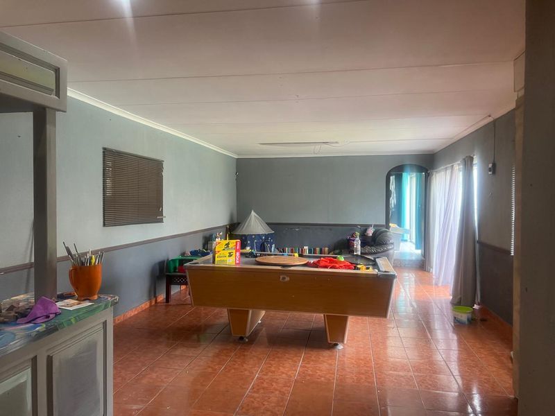 Spacious living area featuring tiled flooring, a built-in bar counter, and an archway leading to an adjacent space with sliding door access.