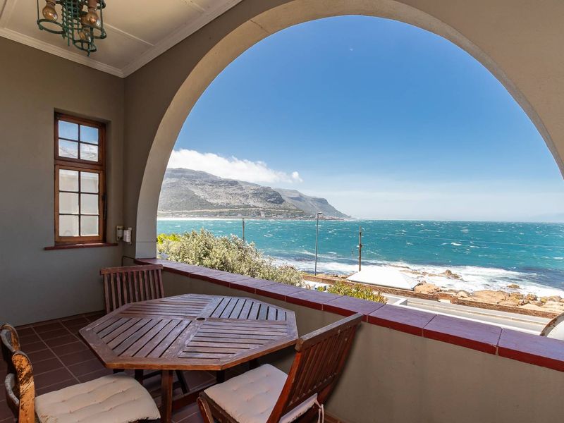 Covered balcony featuring a distinctive arched opening with panoramic ocean and mountain views, finished with tiled flooring and terracotta capping.