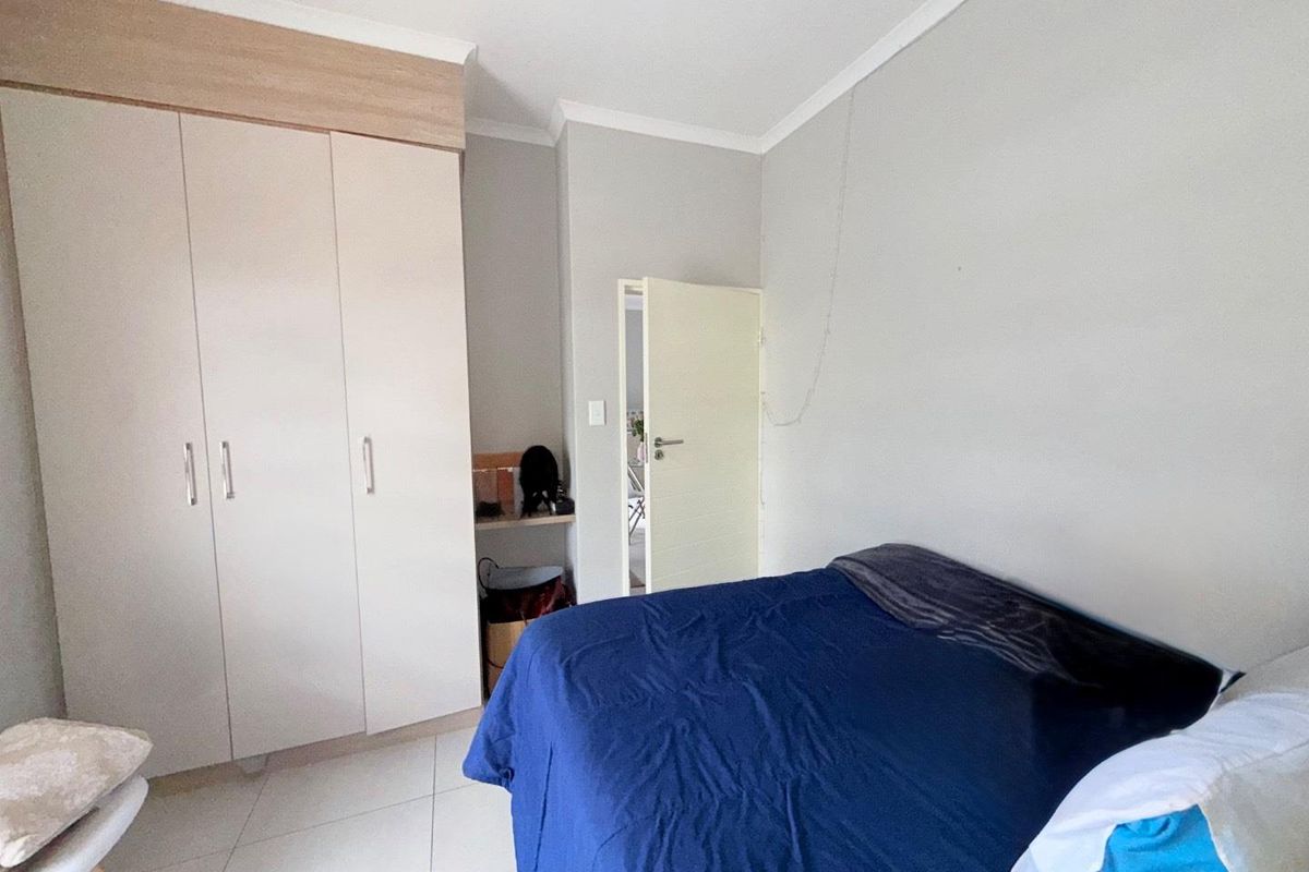 A bedroom featuring built-in cabinetry with light wood-tone accents and tiled flooring, providing functional storage space.