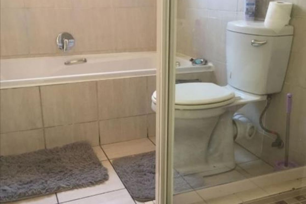 A functional bathroom featuring a bathtub, a separate shower enclosure, and a standard toilet with neutral ceramic wall and floor tiling.