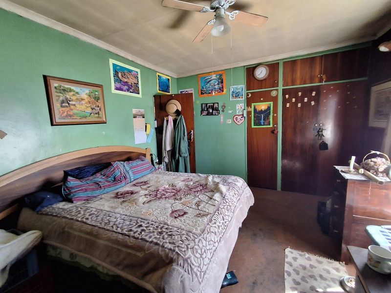 A bedroom featuring built-in wooden cupboards and a ceiling fan, requiring cosmetic updates to improve the overall condition and aesthetic appeal.
