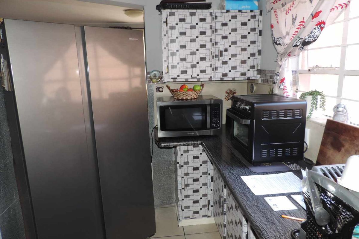 A compact kitchen area featuring dark laminate countertops, patterned cabinetry, and tiled flooring, providing a functional workspace for daily meal preparation.