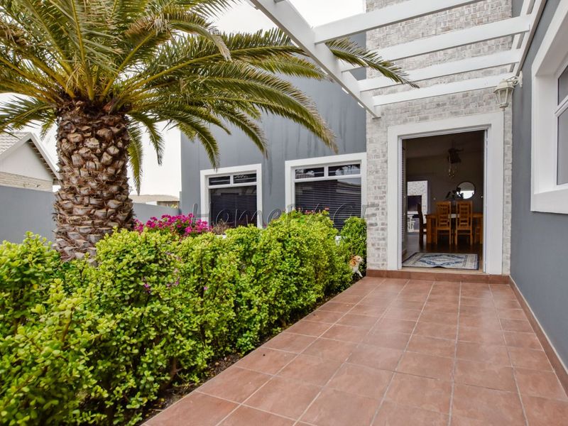 A well-maintained covered patio featuring tiled flooring and a pergola, providing a seamless transition to the interior living space.