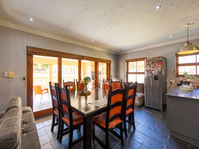 Open-plan dining and kitchen area featuring slate tile flooring, recessed lighting, and large sliding doors providing direct access to the outdoor patio.