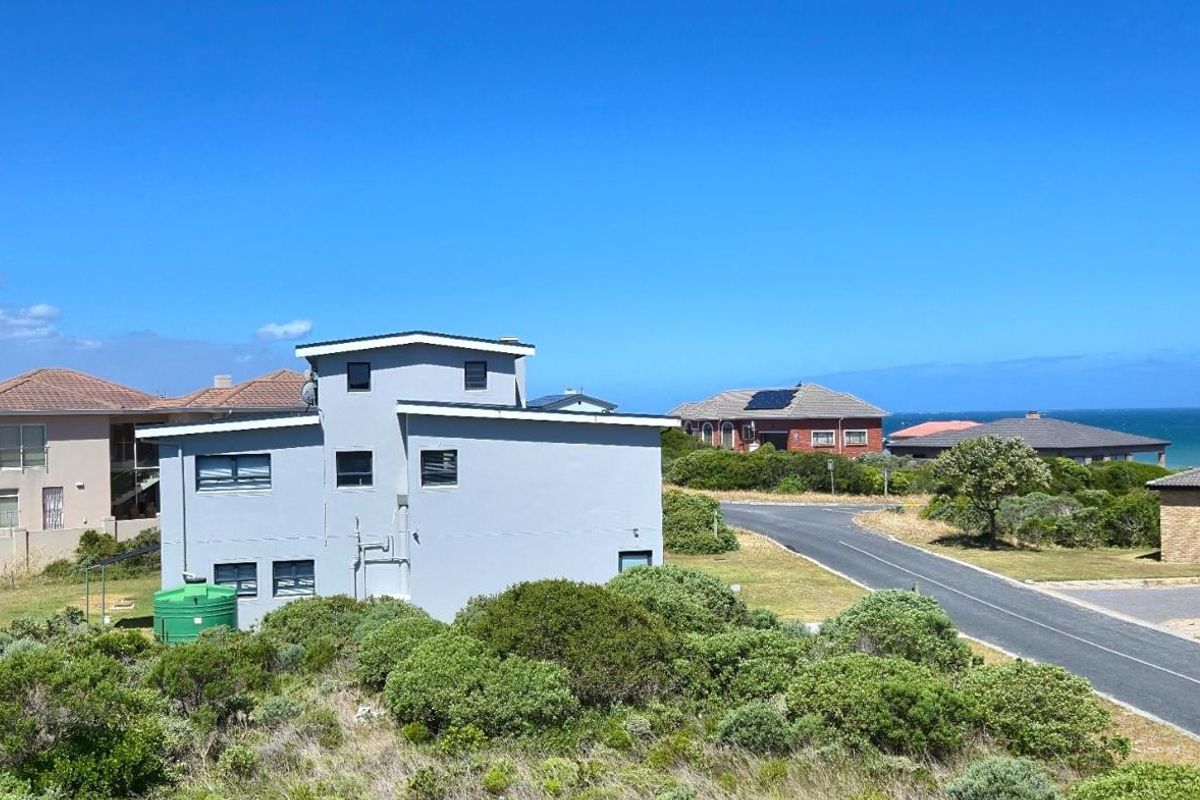 An elevated view of the coastal residential neighborhood, showcasing the property's position relative to the street and surrounding homes with ocean views.
