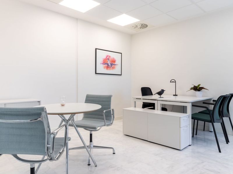 A bright, modern office space featuring clean white walls, recessed ceiling lighting, and polished marble flooring, creating a professional and well-maintained work environment.