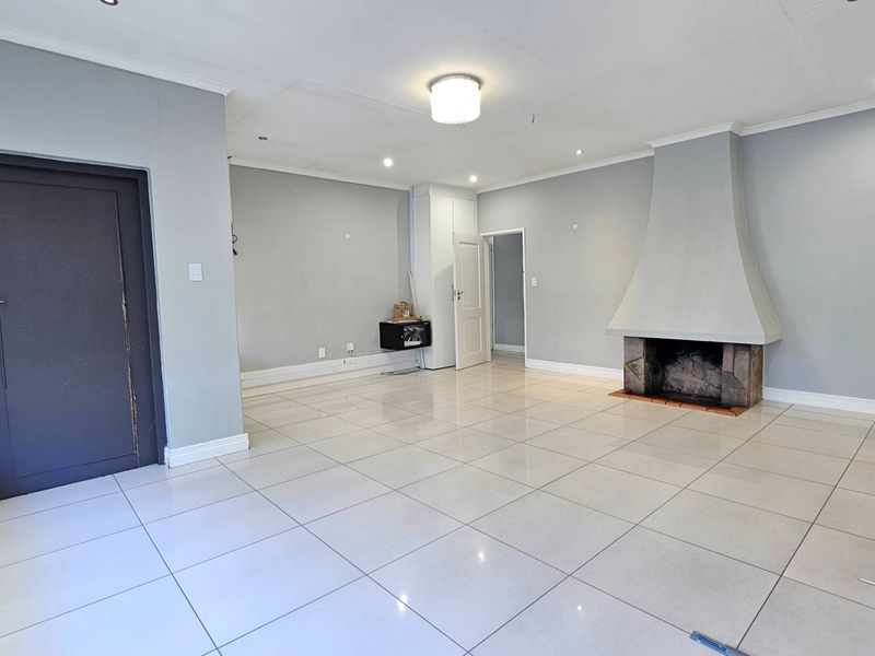 Spacious living room featuring large format floor tiles, a prominent built-in fireplace, and neutral wall finishes, offering a blank canvas for interior design.