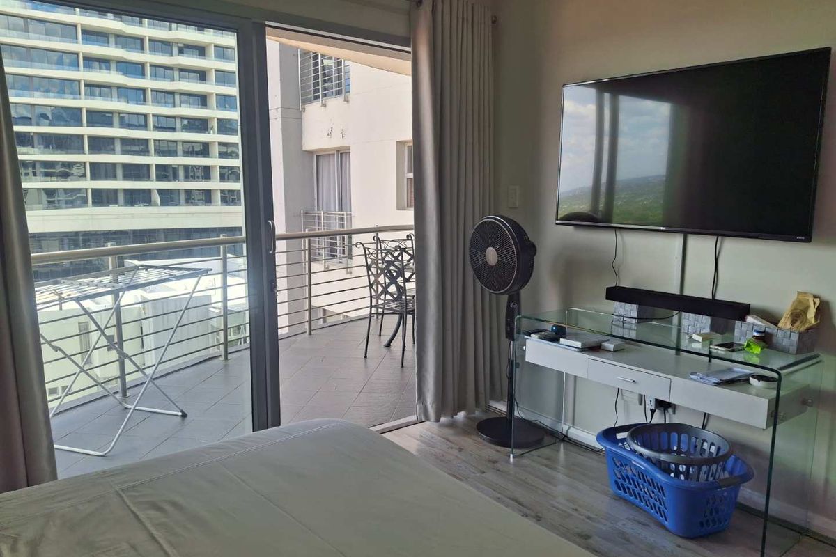 Bedroom featuring laminate flooring and a sliding glass door providing direct access to a private balcony with urban views.