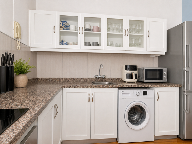 A well-maintained kitchen featuring white shaker cabinetry, granite countertops, a tiled backsplash, and an integrated washing machine.