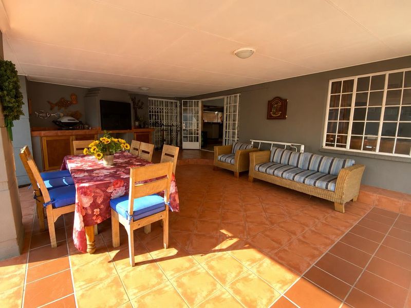 Covered patio area featuring terracotta floor tiles, a built-in braai, and direct access to the interior through french doors.