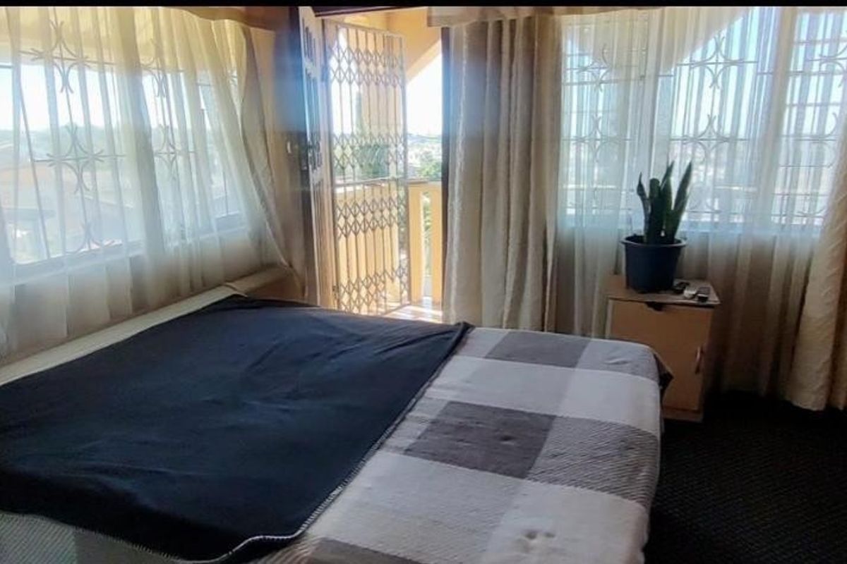 A bedroom featuring built-in cupboards, security bars on the windows, and direct access to a balcony through a security gate.