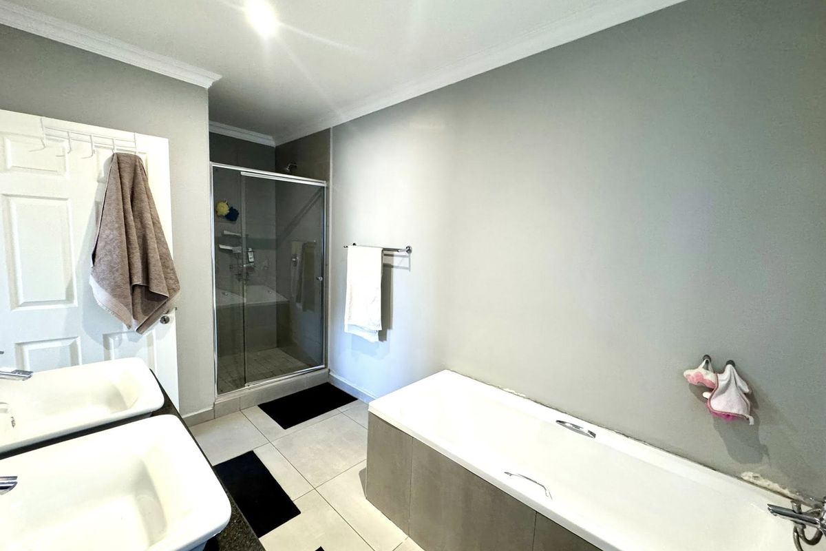 A functional bathroom featuring a double vanity, a separate shower enclosure, and a built-in bathtub with neutral wall finishes.