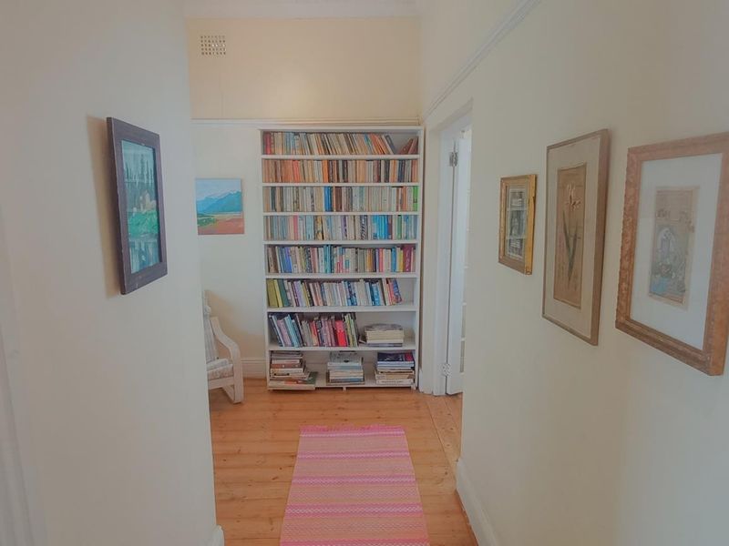 A bright hallway featuring polished timber flooring, classic picture rails, and neutral wall finishes, providing access to adjoining rooms.