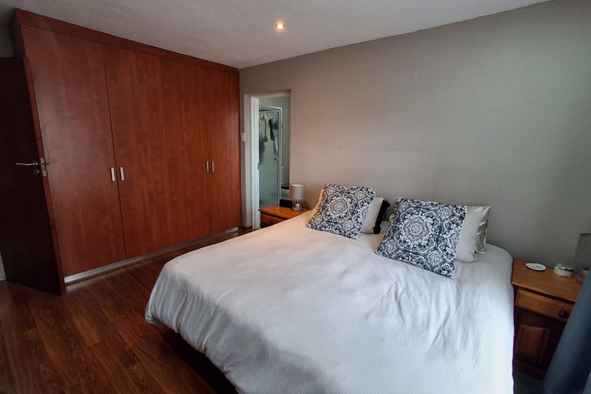 A bedroom featuring laminate flooring, built-in wooden cupboards, and an en-suite bathroom access.