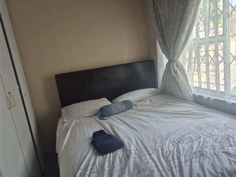 A functional bedroom featuring a built-in wardrobe and a window fitted with a security gate for added safety.