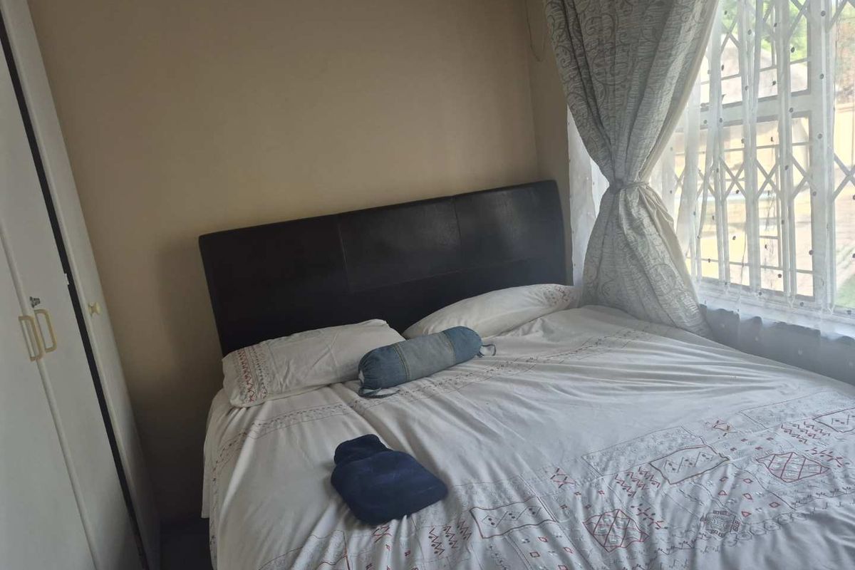A functional bedroom featuring a built-in wardrobe and a window fitted with a security gate for added safety.