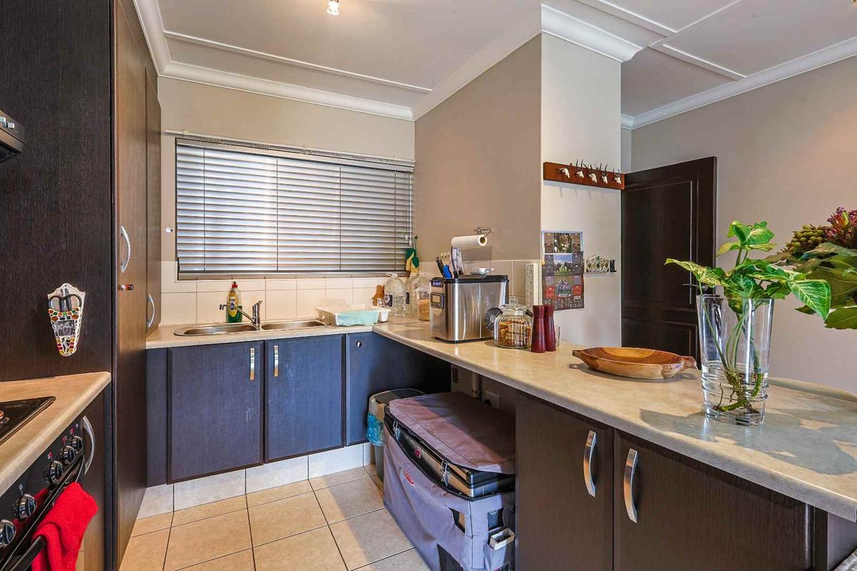 A functional kitchen featuring dark cabinetry, a double sink, tiled flooring, and a breakfast bar counter.
