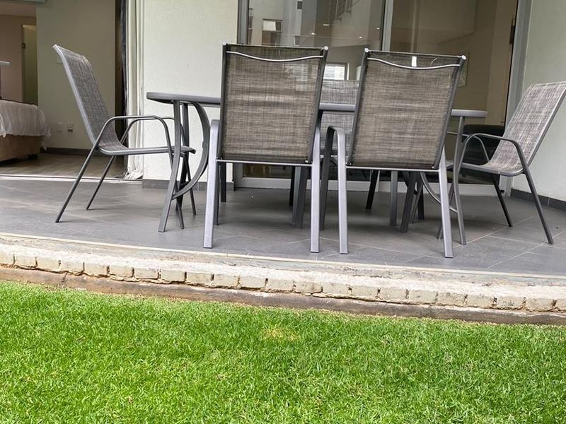Covered patio area with tiled flooring and sliding glass door access to the interior, overlooking a private garden space.