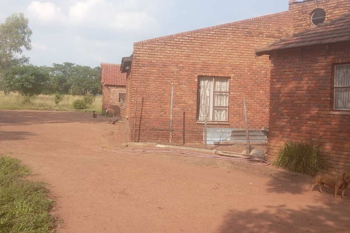 Exterior view of a rustic brick building on agricultural land, featuring exposed brick walls and simple window frames.