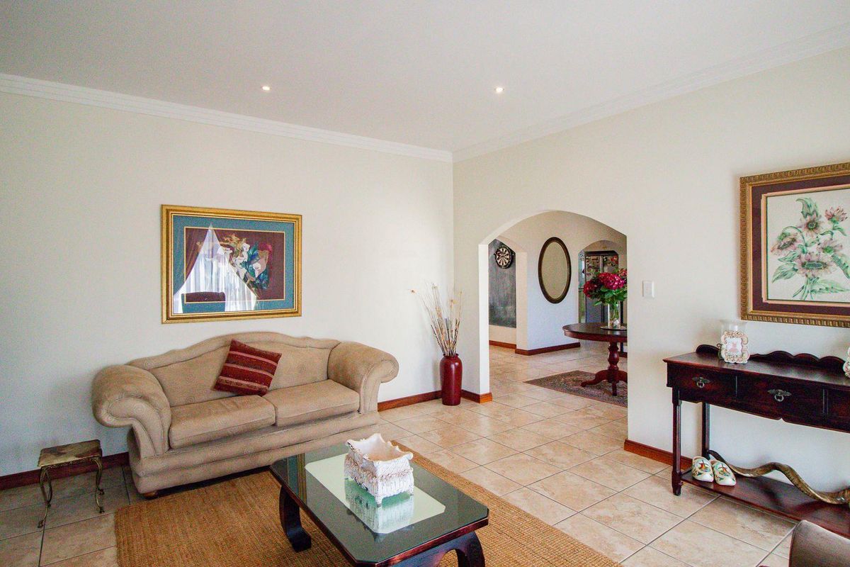 A spacious living area featuring neutral walls, tiled flooring, and an arched entryway leading to an adjacent room.