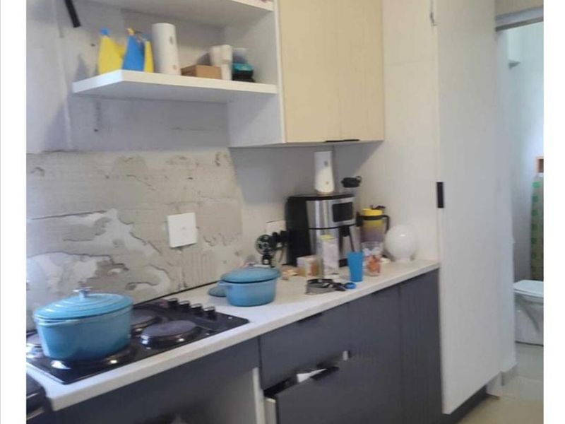Compact kitchen featuring built-in cabinetry, a hob, and microwave space, currently requiring wall finishing and minor repairs to cabinetry.