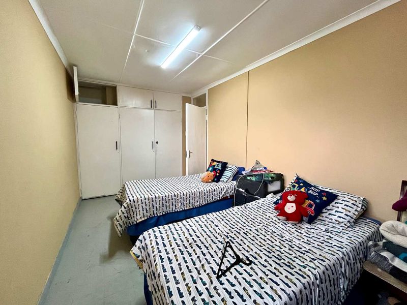 A functional bedroom featuring built-in cupboards and overhead lighting, offering a practical layout with potential for cosmetic updates to enhance the space.