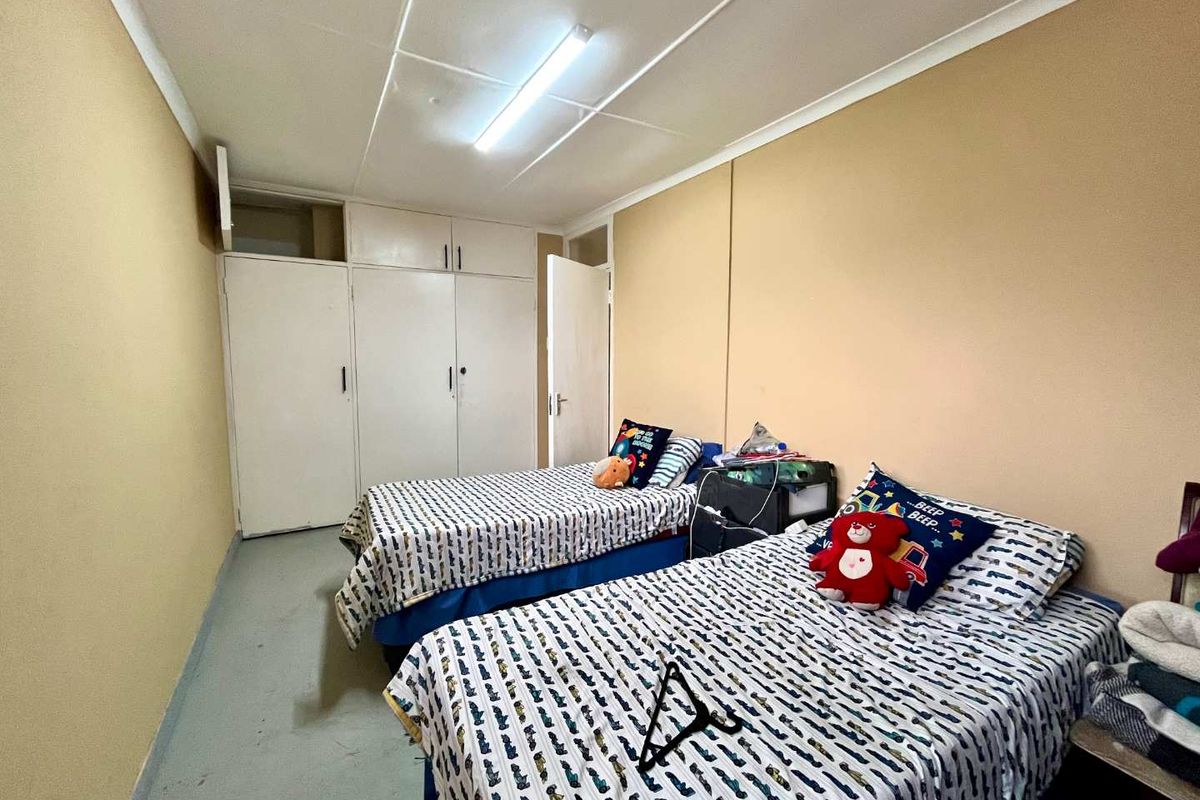 A functional bedroom featuring built-in cupboards and overhead lighting, offering a practical layout with potential for cosmetic updates to enhance the space.