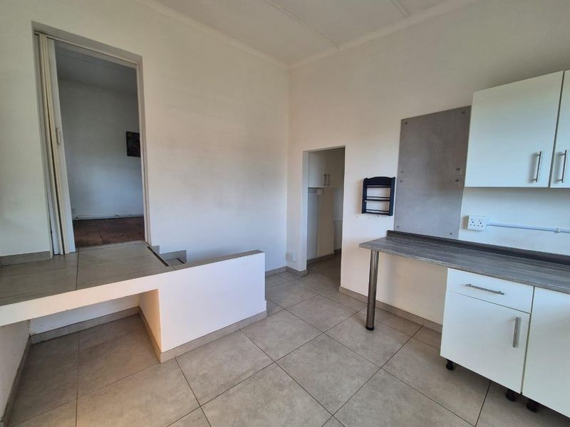 A functional kitchen area featuring tiled flooring, built-in cabinetry, and a laminate countertop, presenting a clean, empty space ready for customization.