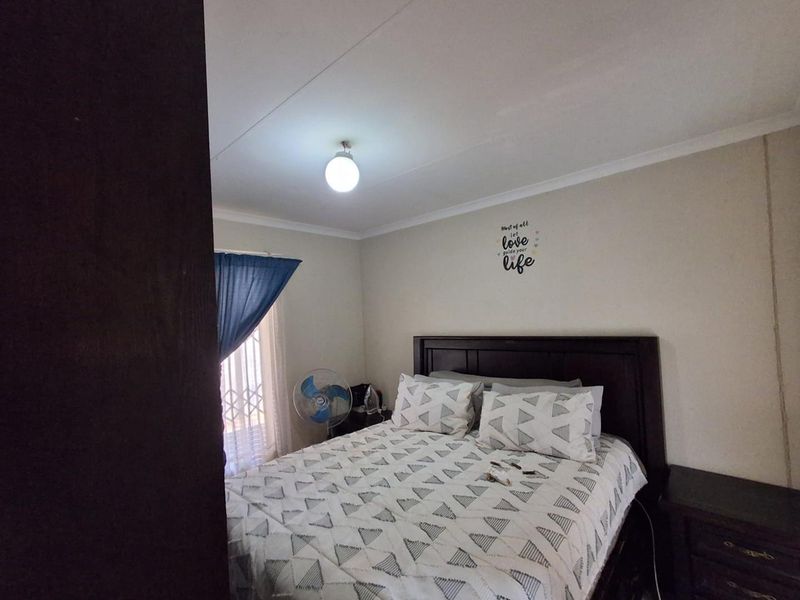 A standard bedroom featuring neutral walls, a security gate on the window, and cove cornicing.