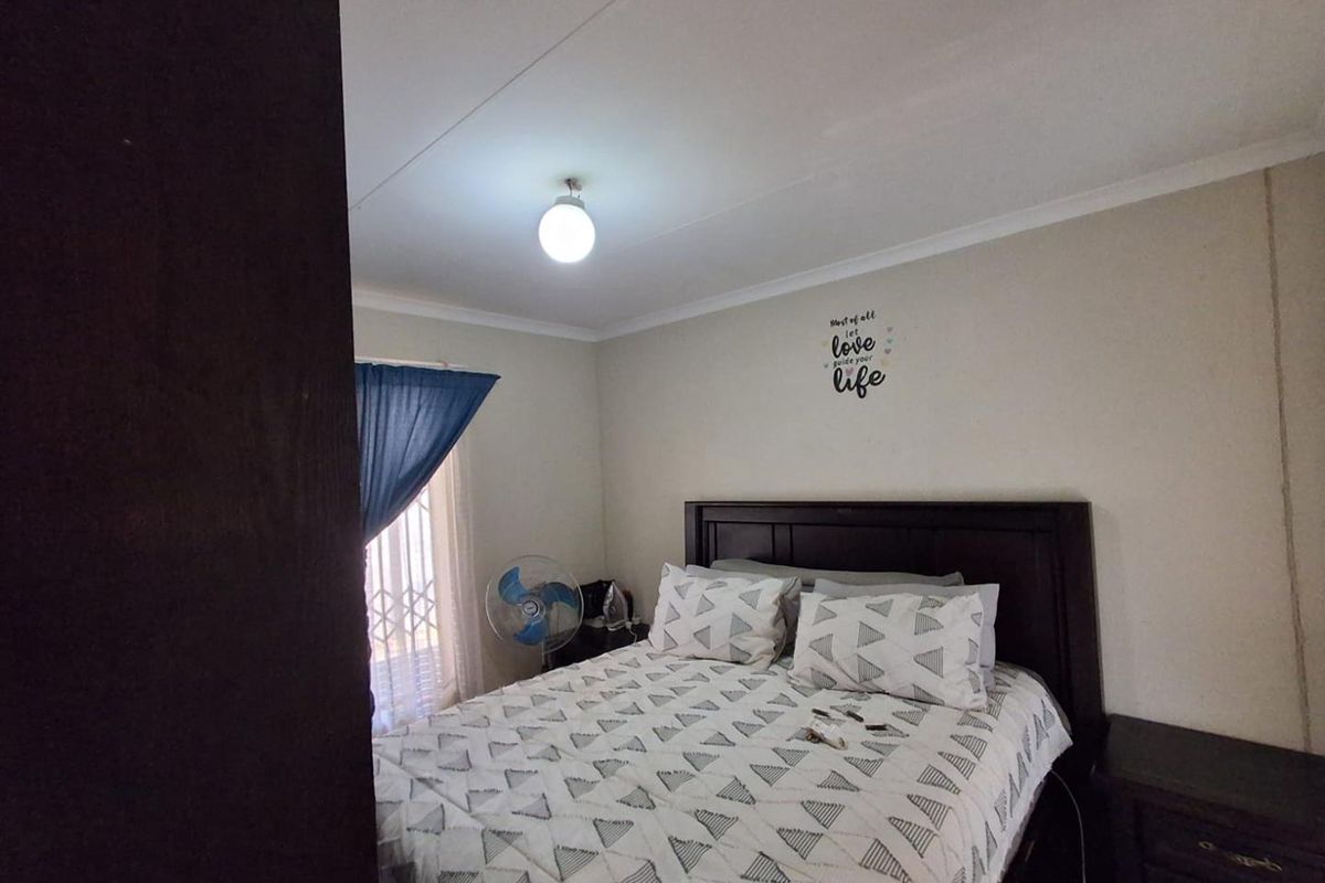 A standard bedroom featuring neutral walls, a security gate on the window, and cove cornicing.