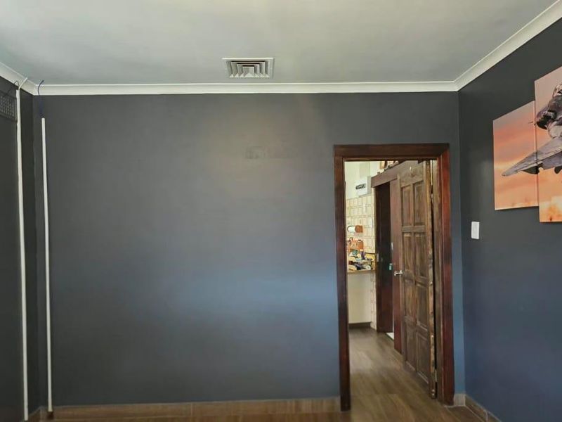 A living room featuring dark grey walls, timber door, and air conditioning unit, providing a neutral base for interior design.