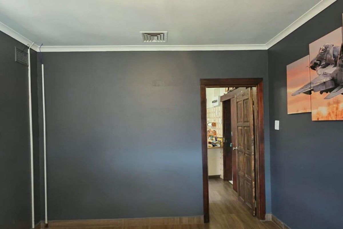 A living room featuring dark grey walls, timber door, and air conditioning unit, providing a neutral base for interior design.