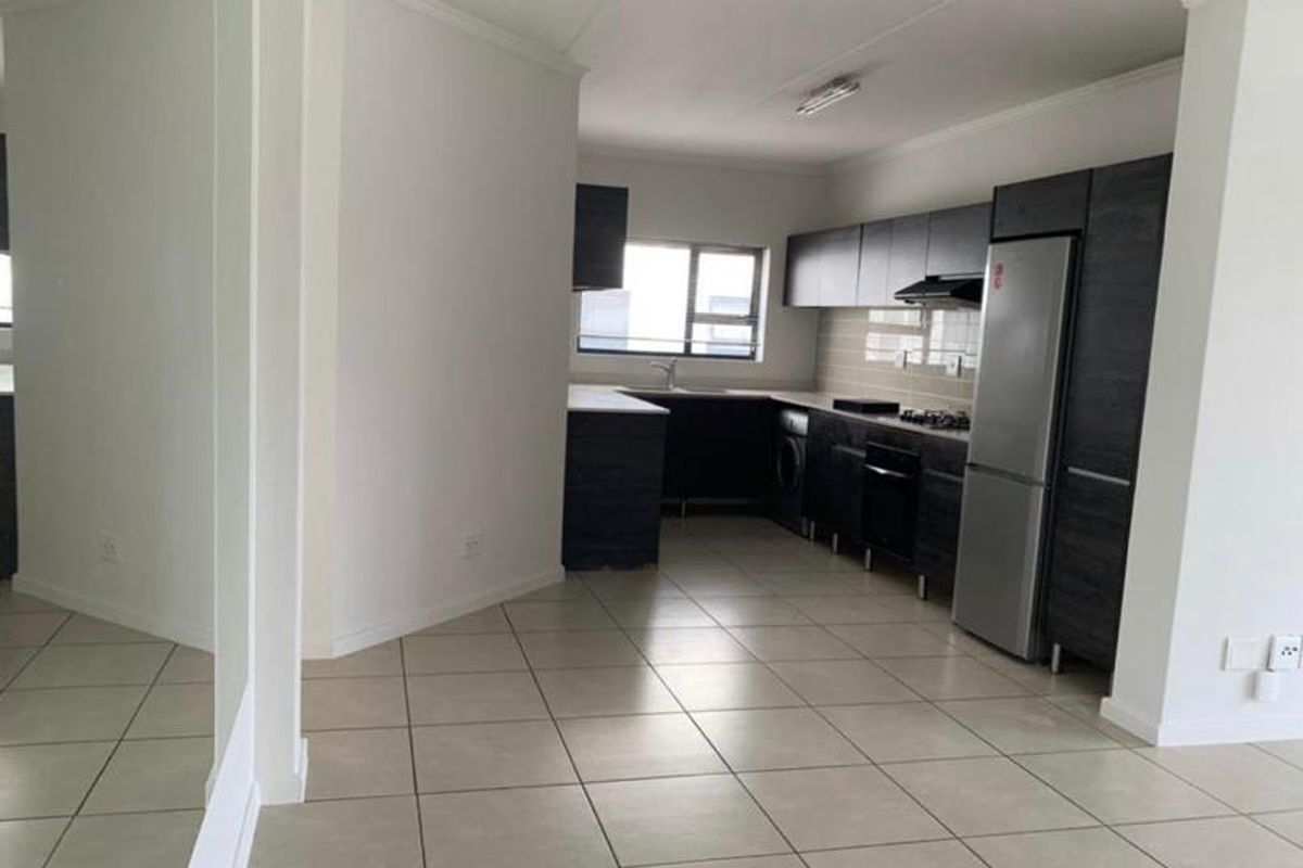 Modern kitchen featuring dark cabinetry, tiled flooring, built-in oven, hob, extractor fan, and a double sink with a tiled backsplash.