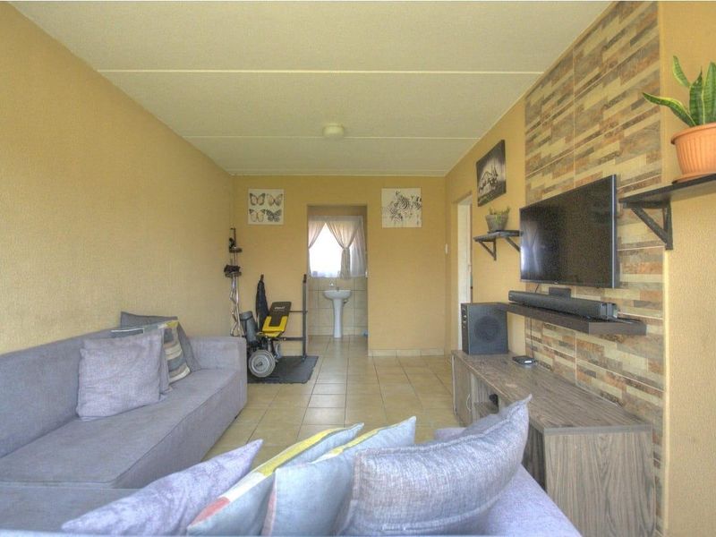 A living room featuring tiled flooring and a stone-cladding feature wall, with an adjacent area containing a pedestal basin.