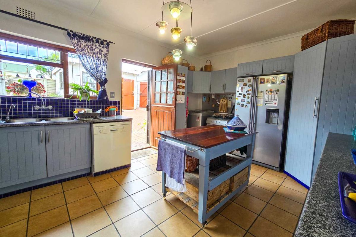 A functional kitchen featuring blue cabinetry, tiled flooring, a double sink, and direct access to an outdoor courtyard area.