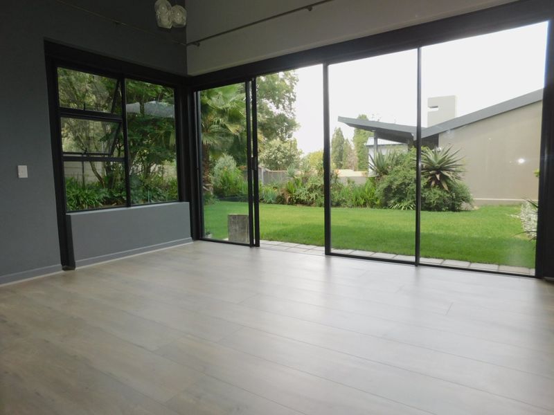 Bright and spacious living area featuring modern laminate flooring and expansive sliding glass doors that provide seamless access to the garden.