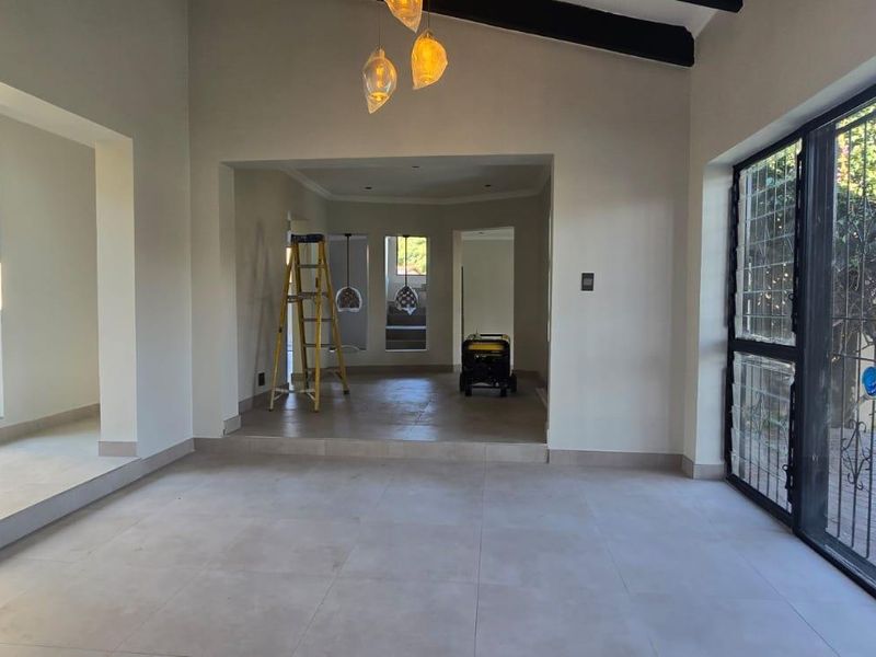 Spacious, light-filled living area featuring vaulted ceilings, neutral tiled flooring, and large sliding glass doors providing direct access to the garden.