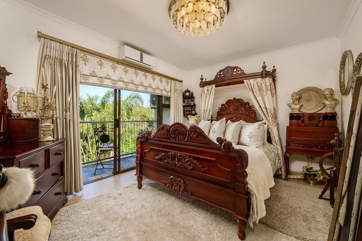 A well-maintained bedroom featuring tiled flooring, a wall-mounted air conditioning unit, and sliding glass doors providing access to a private balcony.