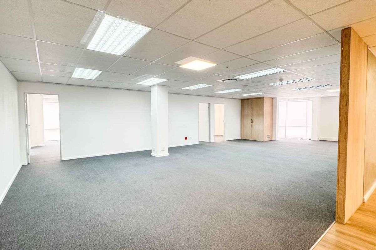 Spacious open-plan office area featuring a suspended ceiling with recessed lighting, neutral carpeting, and integrated storage cabinetry.