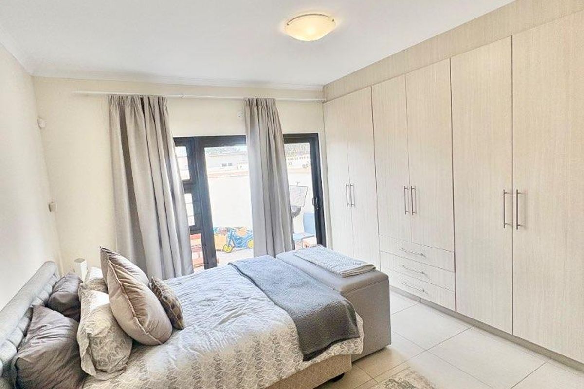 A well-maintained bedroom featuring built-in light wood cabinetry, tiled flooring, and sliding door access to an outdoor area.