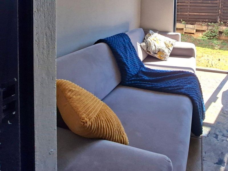 A covered patio area featuring tiled flooring and access to an outdoor garden space.